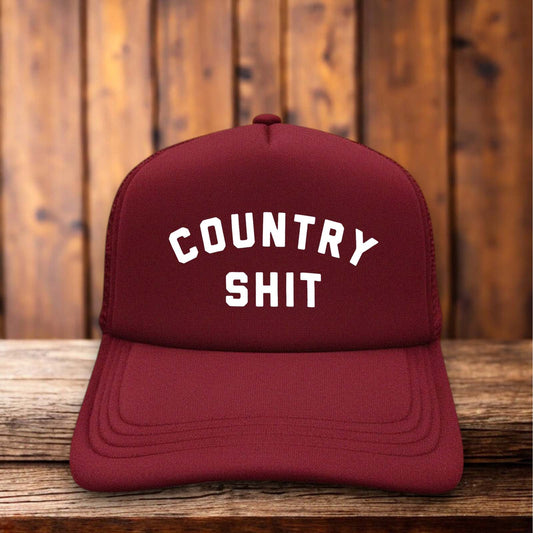 A two-toned vintage-style trucker hat with "Country Shit" in bold, distressed typography.