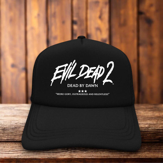 A retro trucker hat featuring the iconic Evil Dead 2 skull with magnifying glass eyes and "Dead By Dawn" typography on a structured foam front.