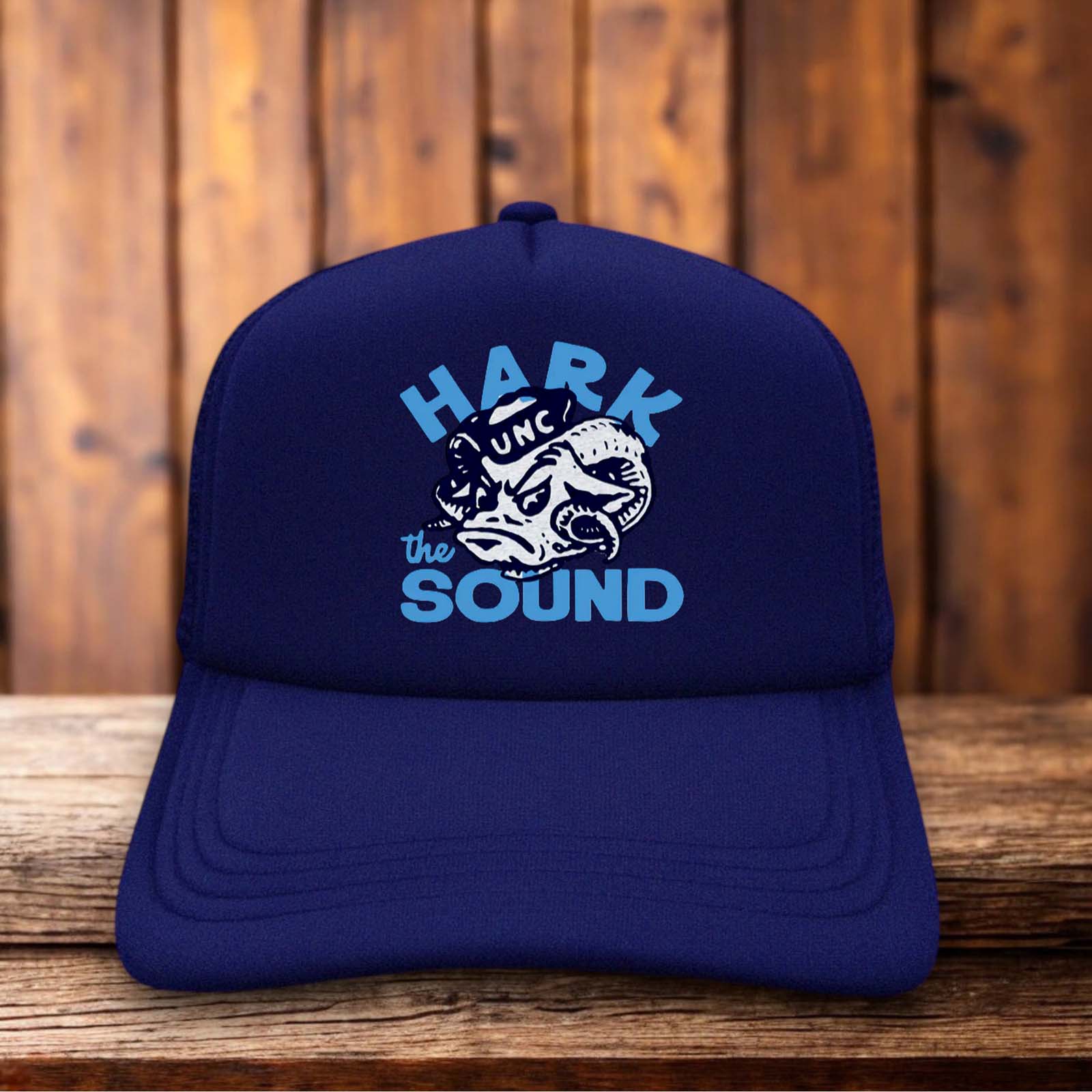 A two-toned polyester trucker hat featuring a vintage UNC Tar Heels Hark The Sound design.