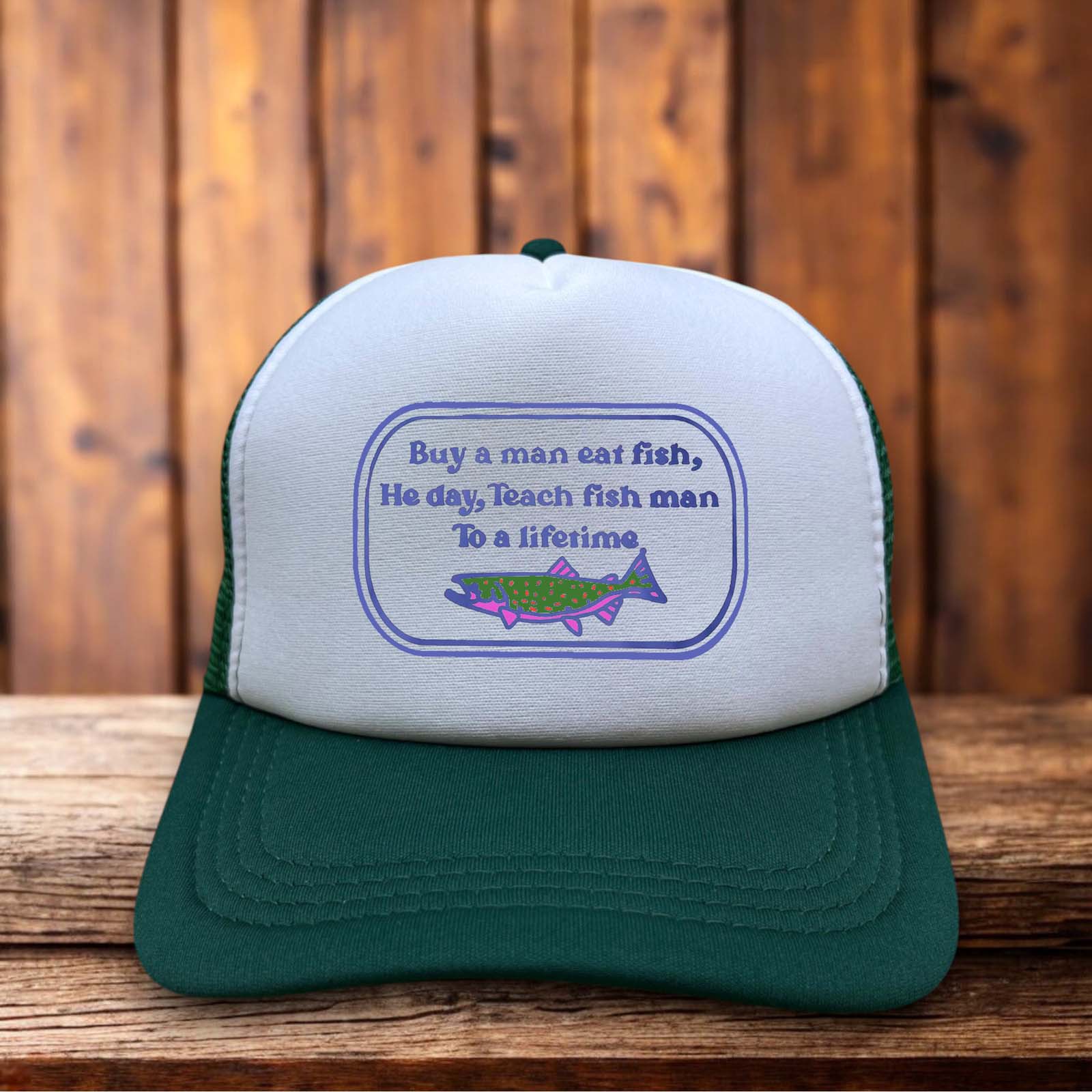 A retro trucker hat featuring the hilariously misquoted "Buy a man eat fish, he day" text in simple, bold typography on a structured foam front.